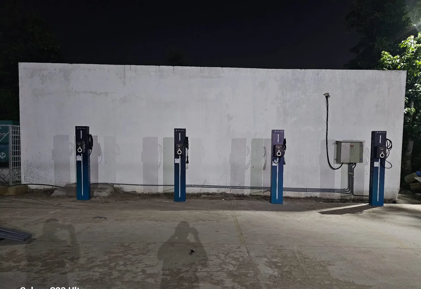 Row of four AC charge posts against a wall with distribution box and concealed cabling