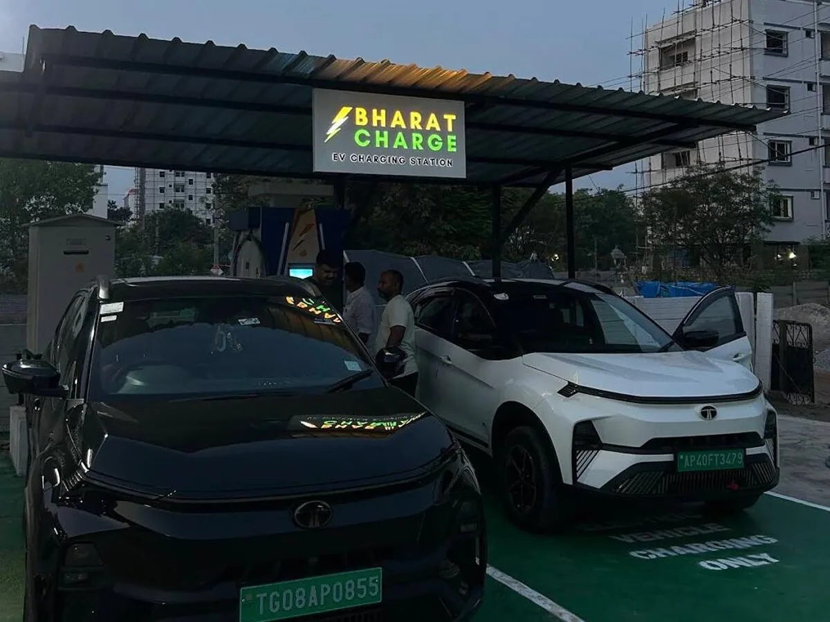 Illuminated Bharat Charge canopy at dusk with two Tata EVs parked on green-marked charging bays