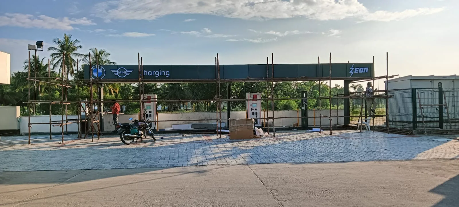 Charging station canopy under construction with scaffolding and chargers being positioned