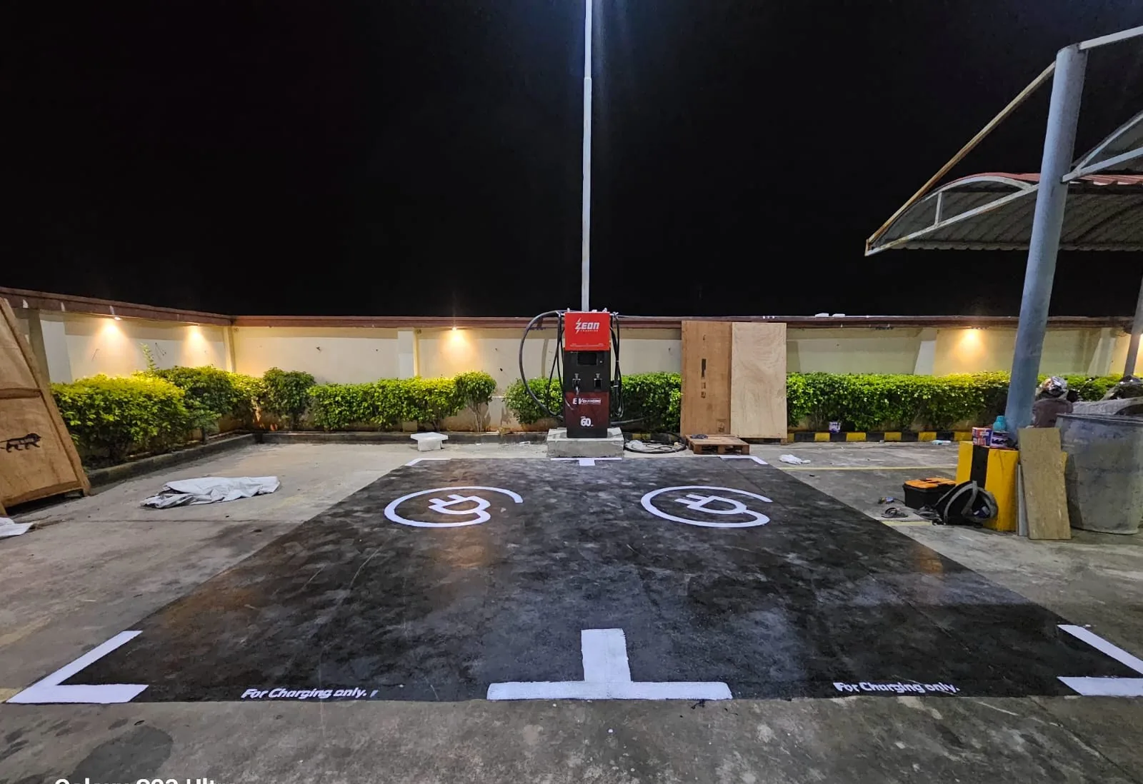 60 kW DC charger on a concrete plinth with freshly painted EV bay marking at night